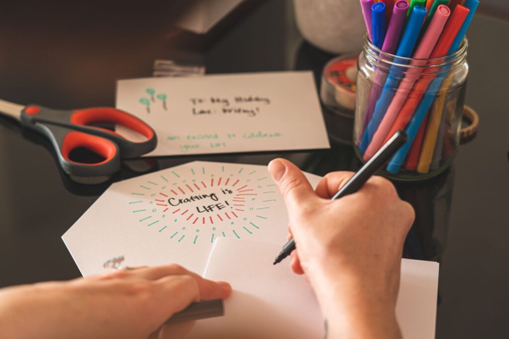 A creative workspace featuring colorful markers, scissors, and a handwritten card reading 'Crafting is Life!'.